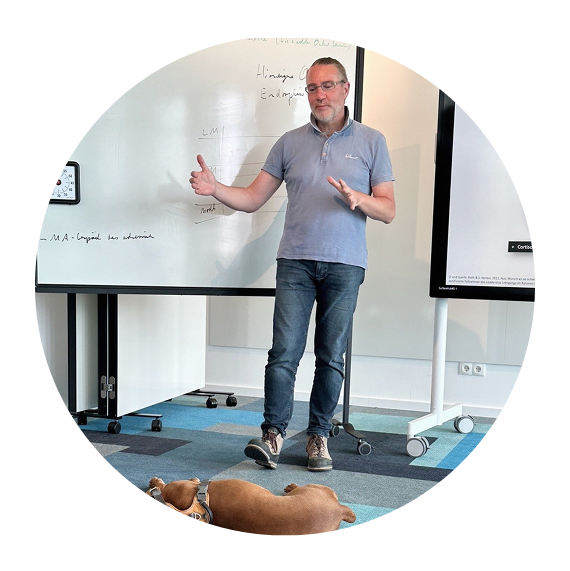Gerd Schmid hält Vortrag vor Whiteboard, sein Hund liegt entspannt vor seinen Füßen